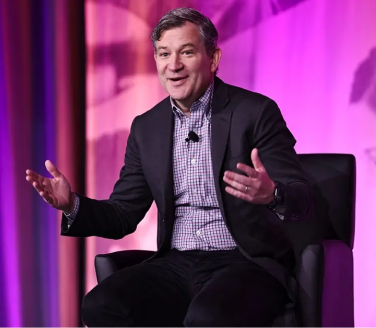 Dan Harris gesturing onstage during a keynote presentation on mindfulness.