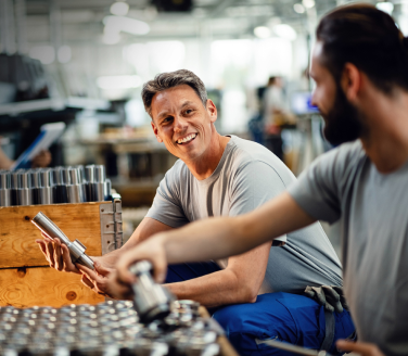 Two smiling Briggs & Stratton employees handling metal parts.