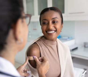 Dr. Natasha Parekh applying a bandage to a person's arm in a clinical setting.