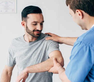 Physical therapist Will Fogarty assessing a person's arm and shoulder in a clinical setting.