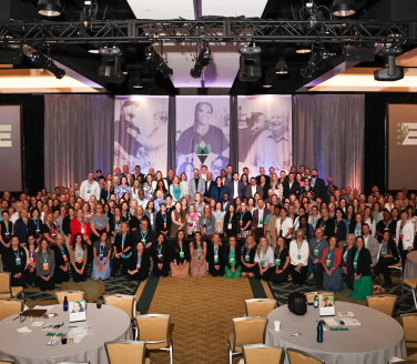 Large group of attendees posing in a ballroom at the Engage 2025 conference.