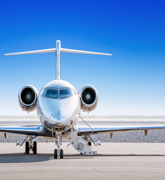 A polished private jet with open boarding stairs parked on a sunlit tarmac under a clear blue sky