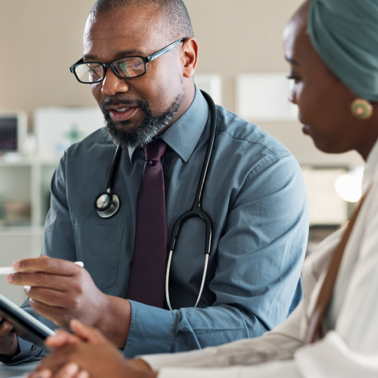 A Missouri doctor with a stethoscope reviews a tablet with a person during an indoor consultation