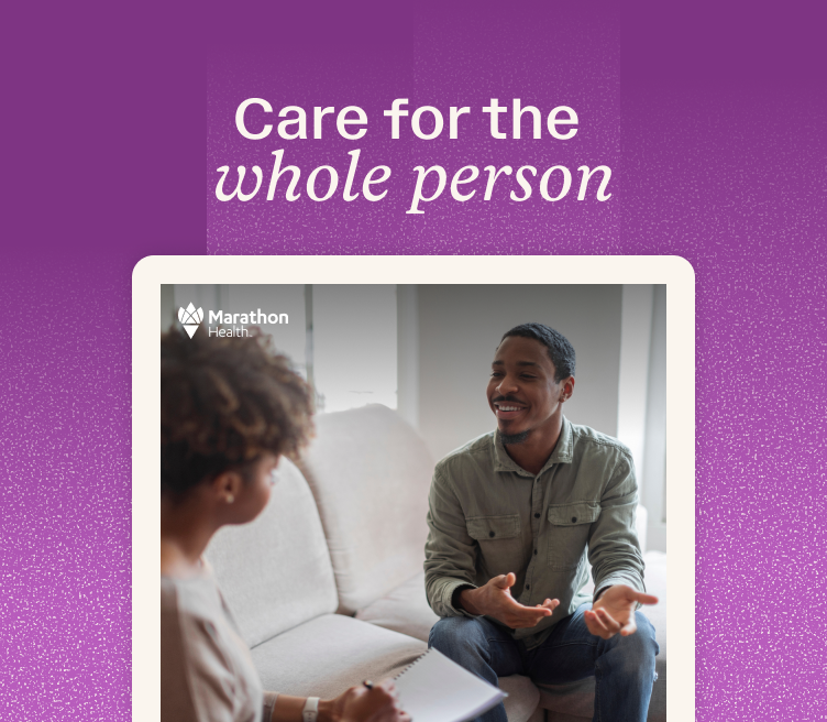 Two people sit across from each other during a LiveBetter mental health session, one smiling and gesturing while the other holds an open notebook.