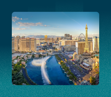 Aerial view of the Las Vegas Strip skyline with hotels, the High Roller, and Bellagio fountains under a blue sky