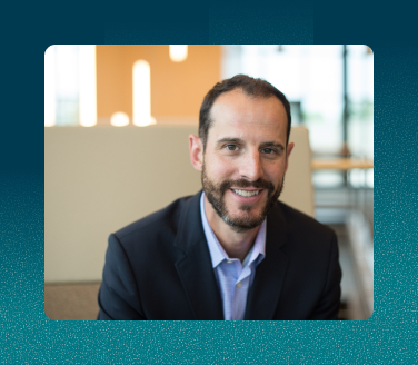 Dr. Jeff Wells smiling in a dark blazer and light blue shirt in a modern office