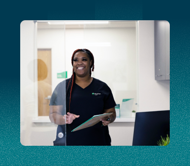 Healthcare professional in scrubs holding a clipboard and smiling inside a Marathon Health clinic