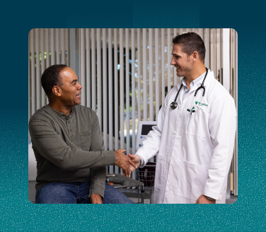 Healthcare provider in a white coat shaking hands with a Tyson Foods employee at a clinic.