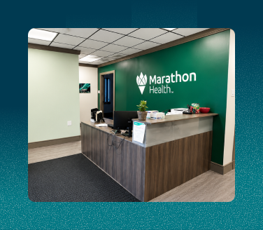 Marathon Health employee health center reception desk with branded green accent wall and logo signage
