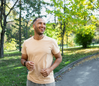 Smiling person jogs along a tree-lined path in a park