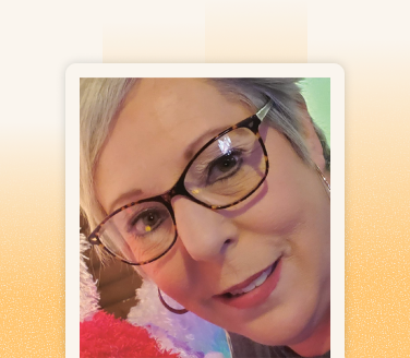 Rebecca Morris smiling in a close-up selfie, wearing tortoiseshell glasses and a red fluffy top